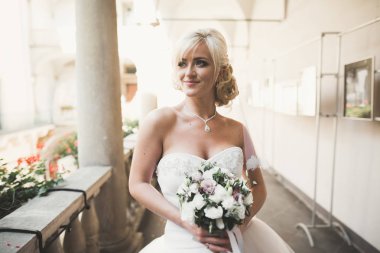 Lüks bir gelin, bir kız buketle poz veriyor ve gülümsüyor.