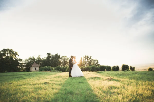 Stilvolles Brautpaar spaziert am Hochzeitstag mit Blumenstrauß durch den Park — Stockfoto