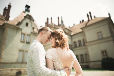 Güzel, romantik bir düğün. Yeni evliler. Eski kalenin yakınlarında sarılıyorlar.