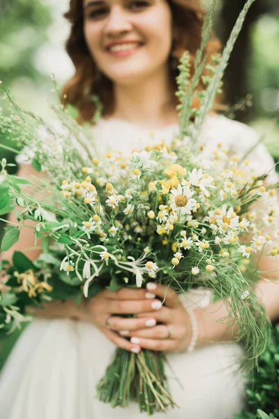 Die Braut mit dem Blumenstrauß im Park. Hochzeit — Stockfoto