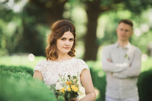 Bruid poseren en glimlacht terwijl bruidegom op de achtergrond wacht — Stockfoto