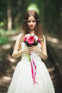 Gelin. Güzel sarışın kadın çiçek çelenk ve buket sıcak yaz gününde park