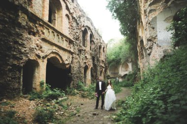 Güzel, romantik bir düğün. Yeni evliler. Eski kalenin yakınlarında sarılıyorlar.