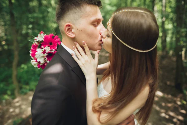Красива молода весільна пара цілується і посміхається в парку — стокове фото