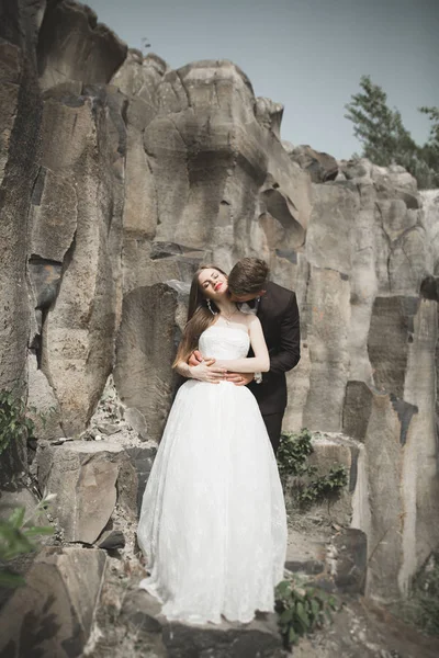 Nádherná nevěsta, ženich, líbání a objímání poblíž útesů s nádherným výhledem — Stock fotografie