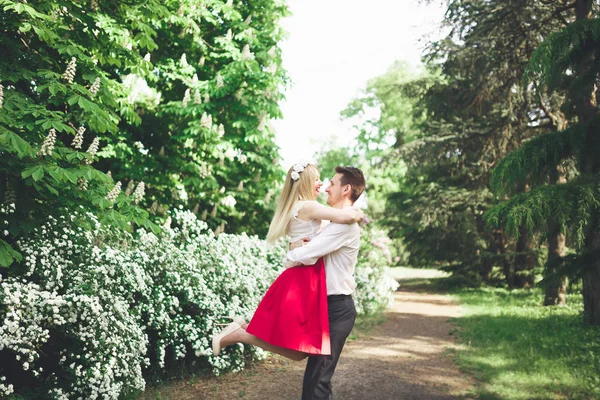 Stilvolle schöne glückliche Hochzeitspaar küsst und umarmt im botanischen Garten — Stockfoto