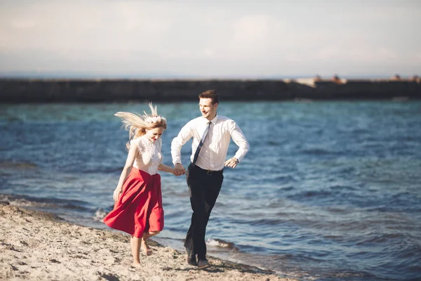 Joven pareja feliz caminando por la playa sonriendo abrazándose unos a otros. Historia de amor — Foto de Stock