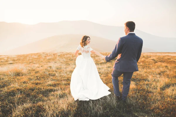 Bröllopsparet poserar på solnedgången vid bröllopsdag. Bruden och brudgummen i kärlek — Stockfoto