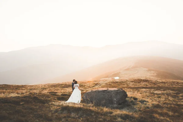 Hermosa pareja de boda posando en la cima de una montaña al atardecer —  Fotos de Stock