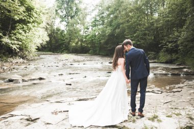 Zarif nazik şık damat ve gelin taşlarla Nehri yakınında. Evlilik çift aşık