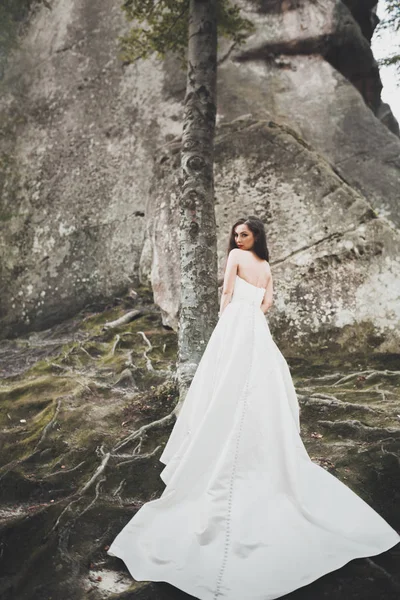 Прекрасная невеста с букетом, позирующим в лесу со скалами. На открытом воздухе — стоковое фото