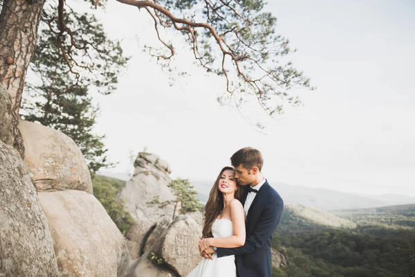 Boda pareja enamorada besándose y abrazándose cerca de rocas en hermoso paisaje — Foto de Stock