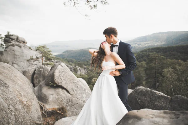 Splendida sposa, sposo baciare e abbracciare vicino alle scogliere con vista mozzafiato — Foto Stock