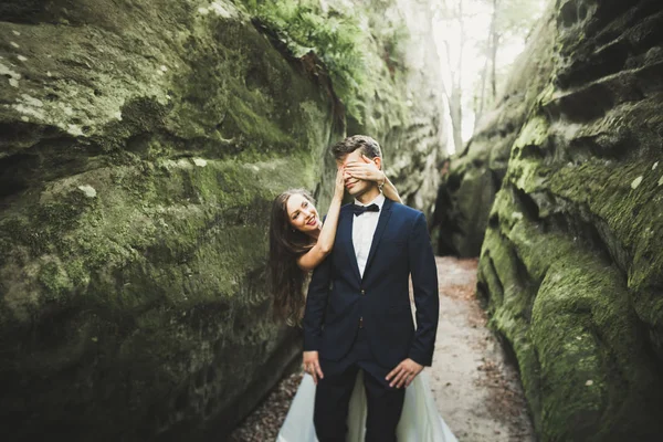 Beau couple heureux jeune mariage posant sur un fond de falaise rocheuse — Photo