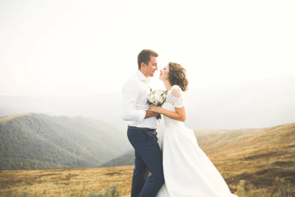 Hochzeitspaar posiert bei Sonnenuntergang am Hochzeitstag. Braut und Bräutigam verliebt — Stockfoto