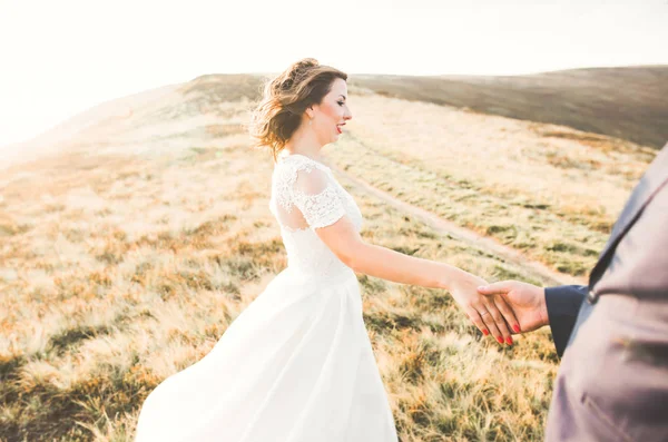 Casal lindo posando no topo de uma montanha ao pôr do sol — Fotografia de Stock