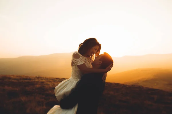 Feliz boda hermosa pareja novia y novio en el día de la boda al aire libre en la roca montañas. Feliz matrimonio pareja al aire libre en la naturaleza, luces suaves y soleadas — Foto de Stock