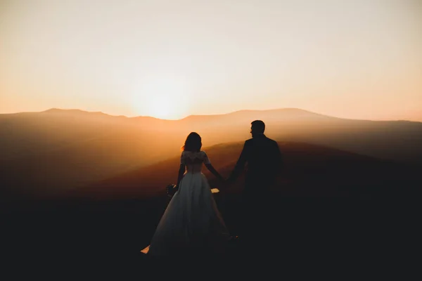Casal lindo posando no topo de uma montanha ao pôr do sol — Fotografia de Stock