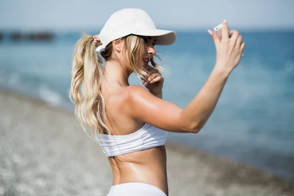 Fitness selfie mulher auto-retrato após o treino. Esporte atleta está tirando fotos selfie depois de trabalhar para fora correndo e treinando ao ar livre na praia — Fotografia de Stock