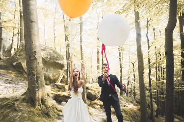 Junge lustige glückliche Hochzeitspaar im Freien mit Luftballons — Stockfoto