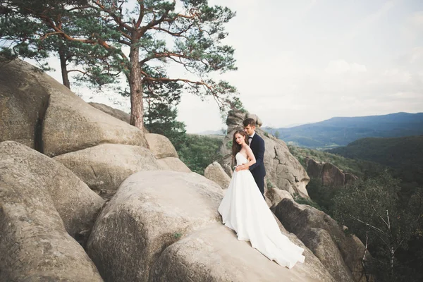 Boda pareja enamorada besándose y abrazándose cerca de rocas en hermoso paisaje — Foto de Stock