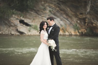 Zarif nazik şık damat ve gelin taşlarla Nehri yakınında. Evlilik çift aşık