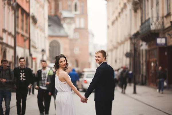 Hermosa pareja de boda, novia, novio besándose y abrazándose de pie en la multitud —  Fotos de Stock