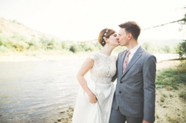 Zarif nazik şık damat ve gelin taşlarla Nehri yakınında. Evlilik çift aşık