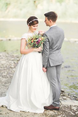 Zarif nazik şık damat ve gelin taşlarla Nehri yakınında. Evlilik çift aşık