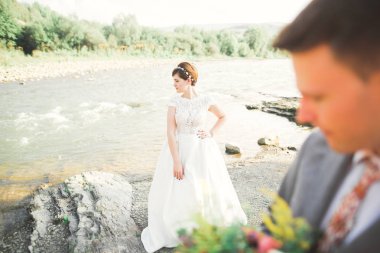 Gelin ve damat güzel düğün buket tutarak. Nehir kenarında poz