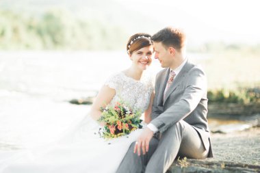 Zarif nazik şık damat ve gelin taşlarla Nehri yakınında. Evlilik çift aşık