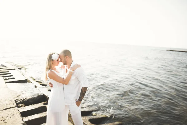 Pareja de recién casados caminando en la playa al atardecer . — Foto de Stock