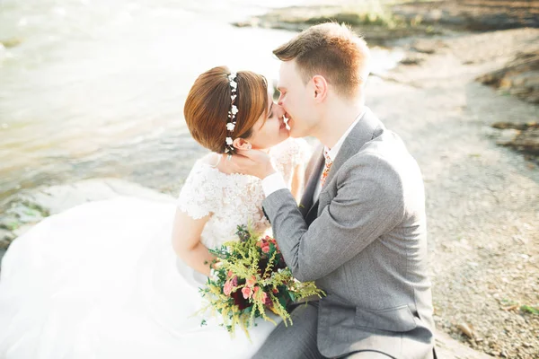 Novia y novio celebrando hermoso ramo de bodas. Posando cerca del río — Foto de Stock