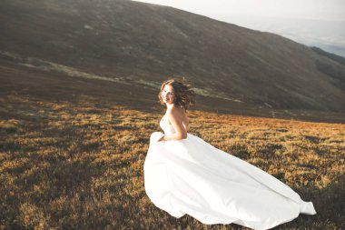 Gün batımında dağ zemin üzerine bir buket ile güzel gelin