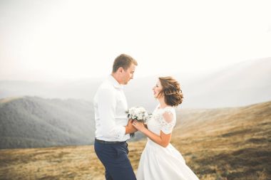 Bir dağın tepesinde günbatımında poz güzel düğün çifti