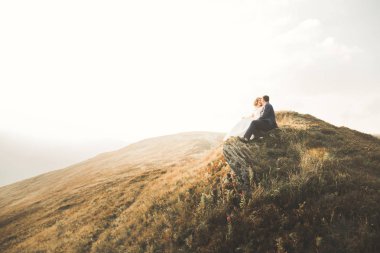 Güzel bir düğün çifti mükemmel bir manzarayla dağda öpüşüyor ve sarılıyor.