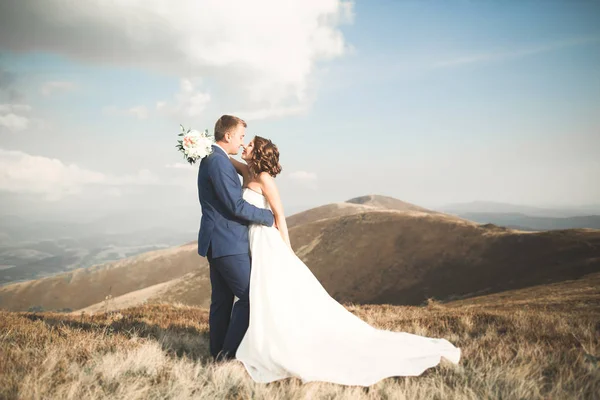 Mooie bruidspaar poseren op de top van een berg bij zonsondergang — Stockfoto