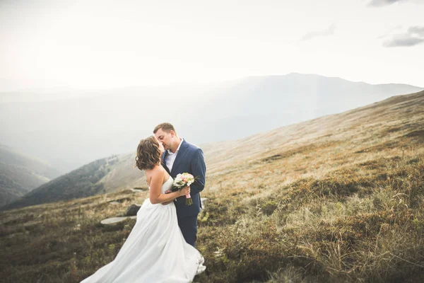 Šťastný svatební pár nevěsta a ženich na svatební den venku na horách skály. Šťastný manželský pár venku na přírodě, měkká slunečná světla — Stock fotografie