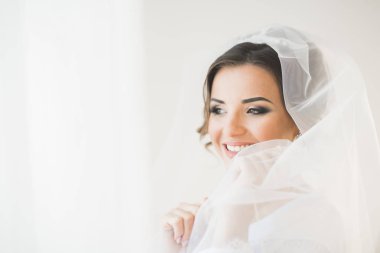 Beyaz elbiseli lüks gelin düğün törenine hazırlanırken poz veriyor.