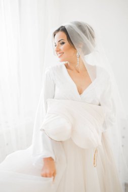 Cüppeli muhteşem gelin bir odada düğün töreni için poz veriyor ve hazırlanıyor.