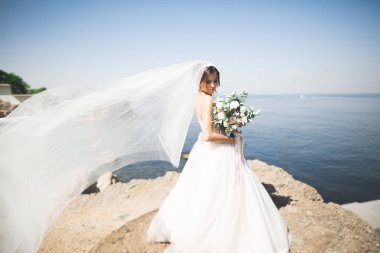 Güzel genç gelin gelin buketi arka plan denizin üzerinde poz ile