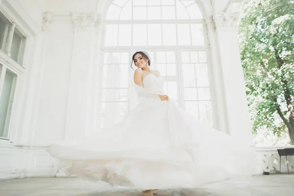 Mooie bruid in trouwjurk met lange volledige rok, witte achtergrond, dansen en lachen — Stockfoto