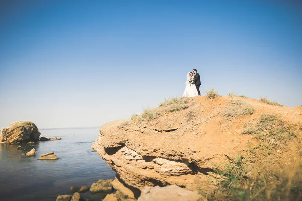 Feliz y romántica escena de recién casada joven pareja de boda posando en la hermosa playa — Foto de Stock