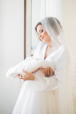 Beyaz elbiseli lüks gelin düğün törenine hazırlanırken poz veriyor.