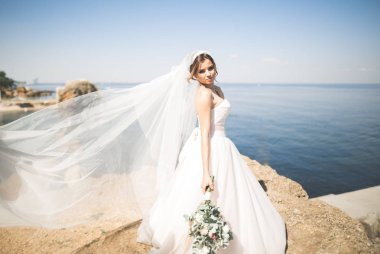 Güzel genç gelin gelin buketi arka plan denizin üzerinde poz ile