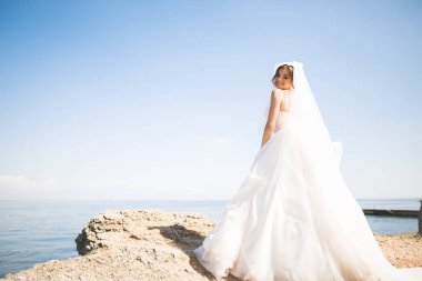 Güzel genç gelin gelin buketi arka plan denizin üzerinde poz ile