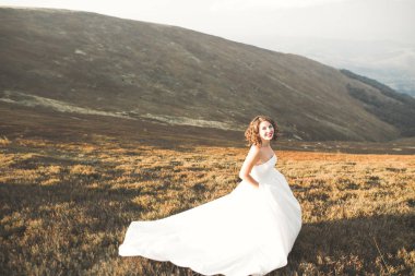 Gün batımında dağ zemin üzerine bir buket ile güzel gelin