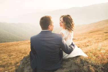 Bir dağın tepesinde günbatımında poz güzel düğün çifti