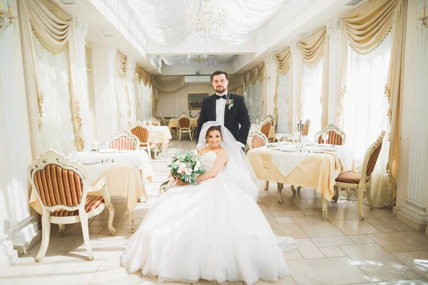 Gorgeous groom gently hugging stylish bride. Sensual moment of luxury wedding couple