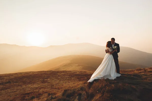 Bruidspaar poseren op zonsondergang op de trouwdag. Bruid en bruidegom verliefd — Stockfoto